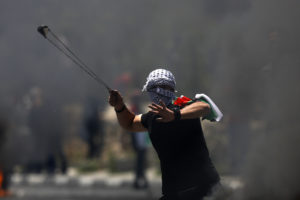 A Palestinian protester hurls a stone during clashes with Israeli forces after a rally to mark the 70th anniversary of what Palestinians call their "nakba."