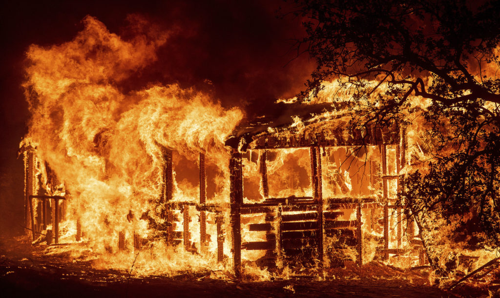 Photo of Carr Fire consuming a building along Highway 299