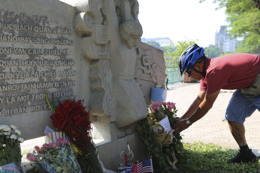Photo of Vietnamese man laying flowers at the memorial for John McCain in Hanoi
