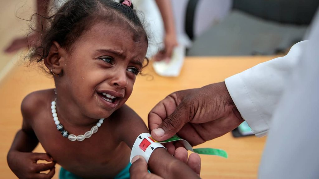 Photo of a Yemeni child getting her arm measured