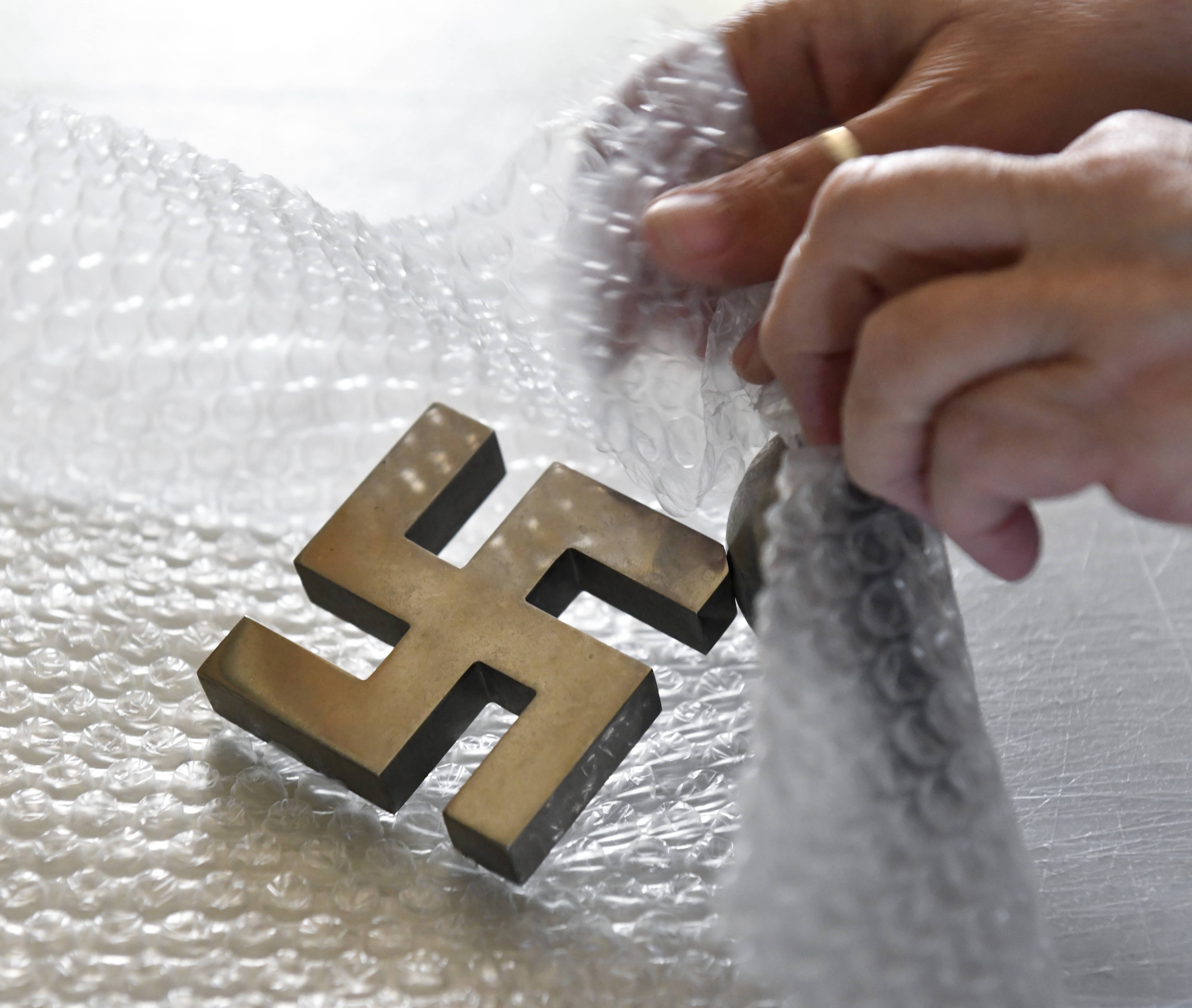 Photo of Tammy Pearce packing a recently sold swastika desk ornament
