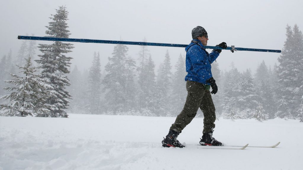 Photo of man carrying snow measuring equipment