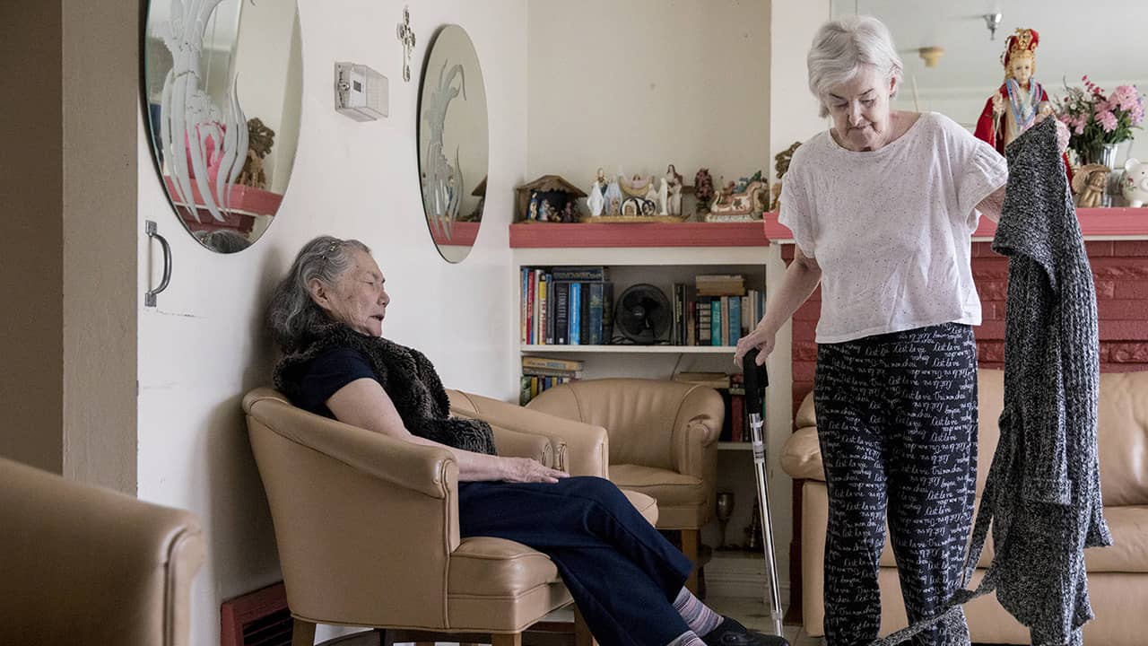 Photo of resident Concepcion Wedell walking past Setsuko Letchford