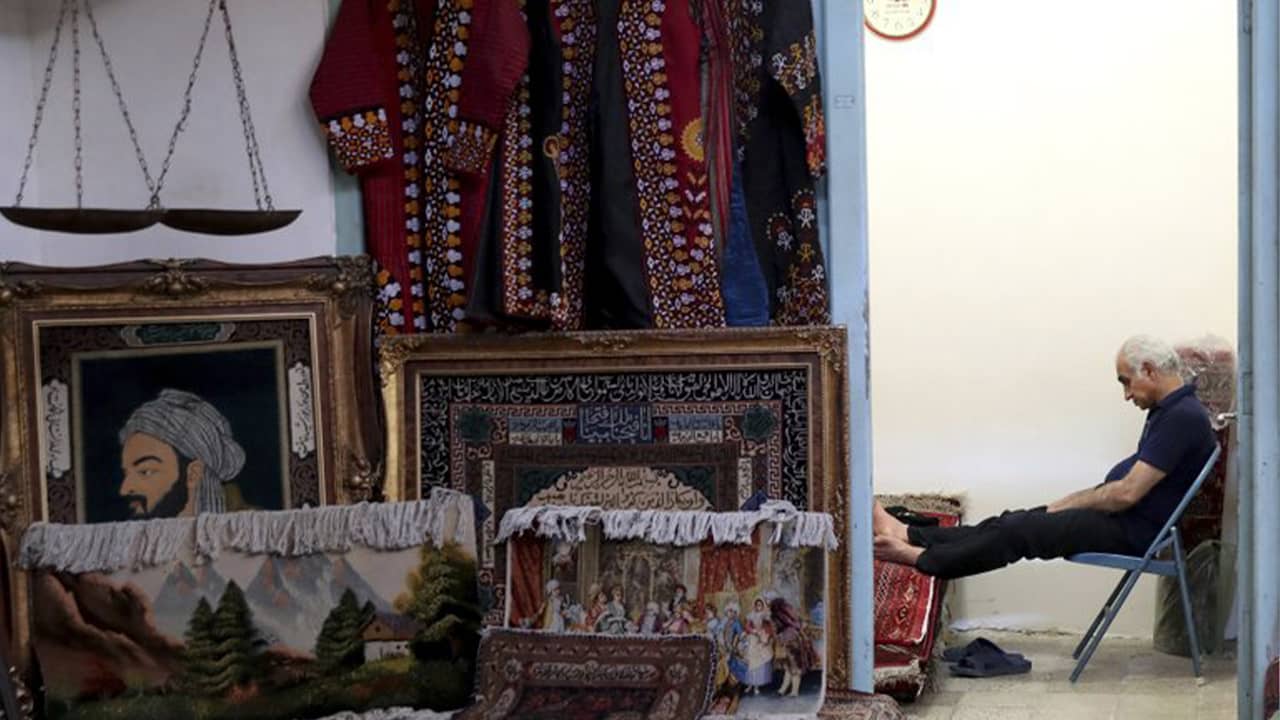 Photo of a carpet seller sitting at his shop in the main bazaar