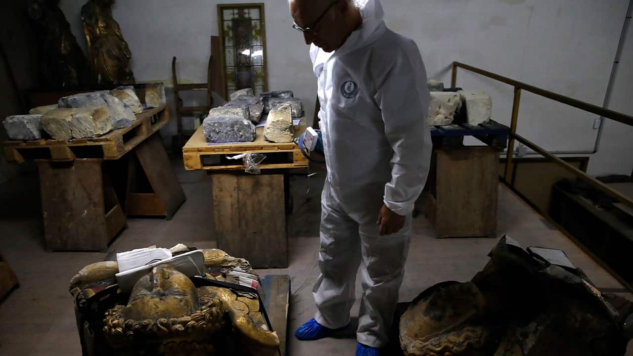 Photo of stone expert Jean-Didier Mertz looking at the remains of the golden angel that was once atop the Notre Dame cathedral