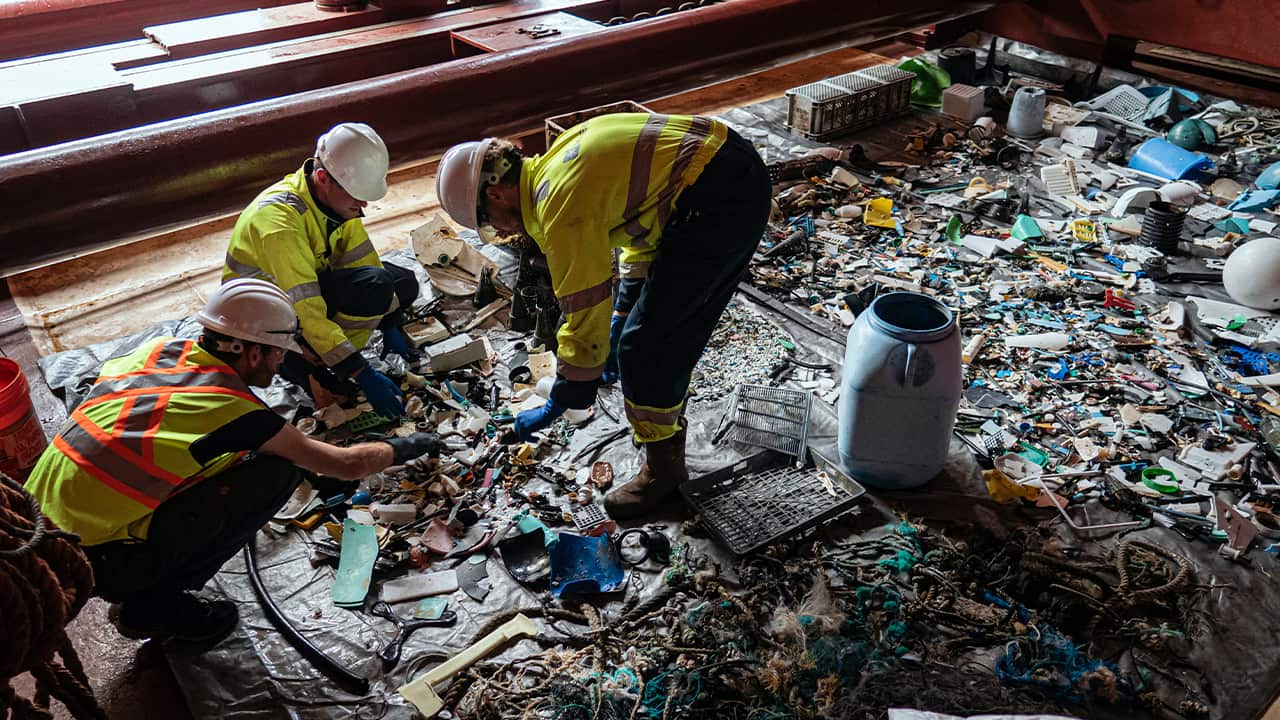 Photo of crew members sorting through plastic on board a support vessel