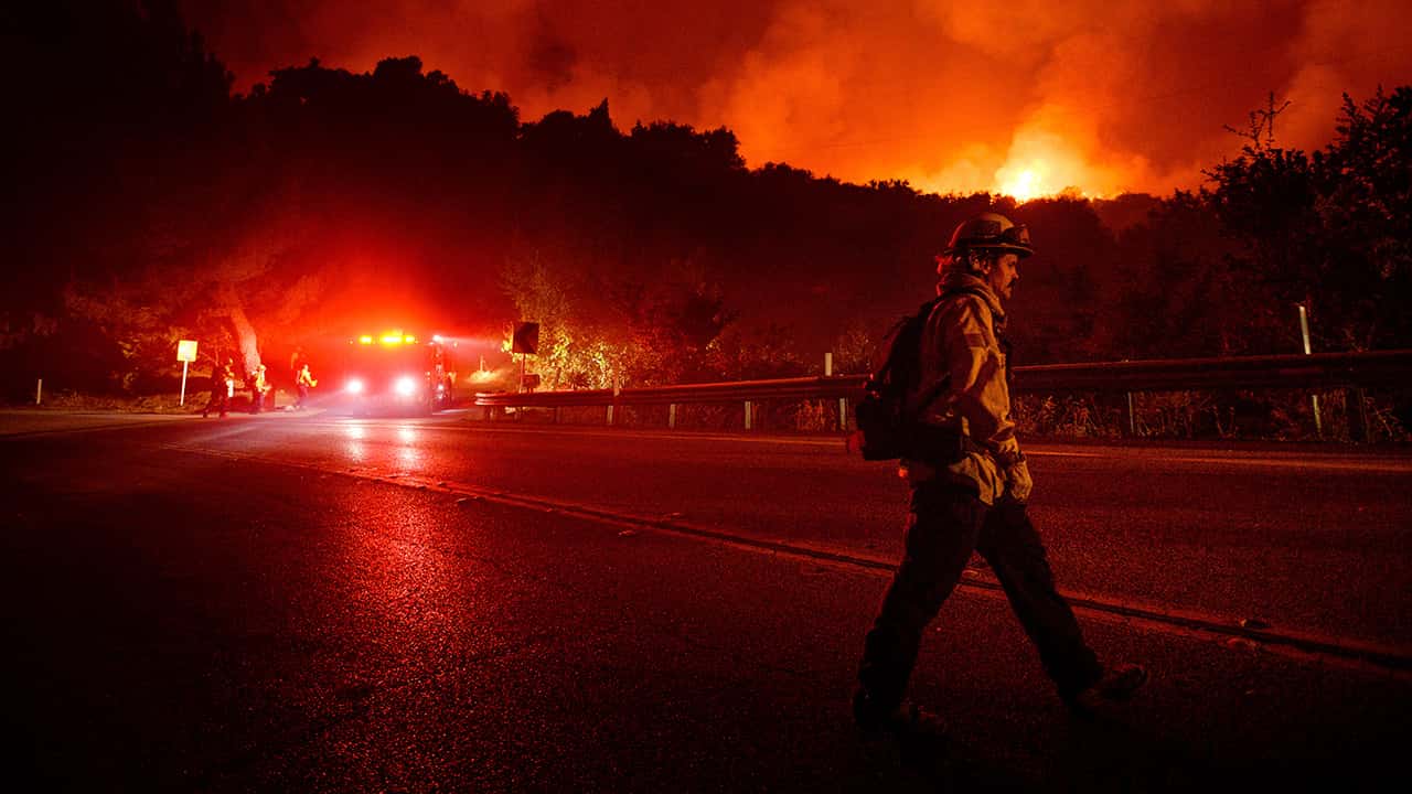 Photo of a firefighter crossing Highway 154 while battling the Cave Fire