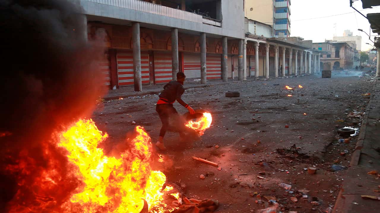 Photo of riot police firing tear gas while protesters set a fire