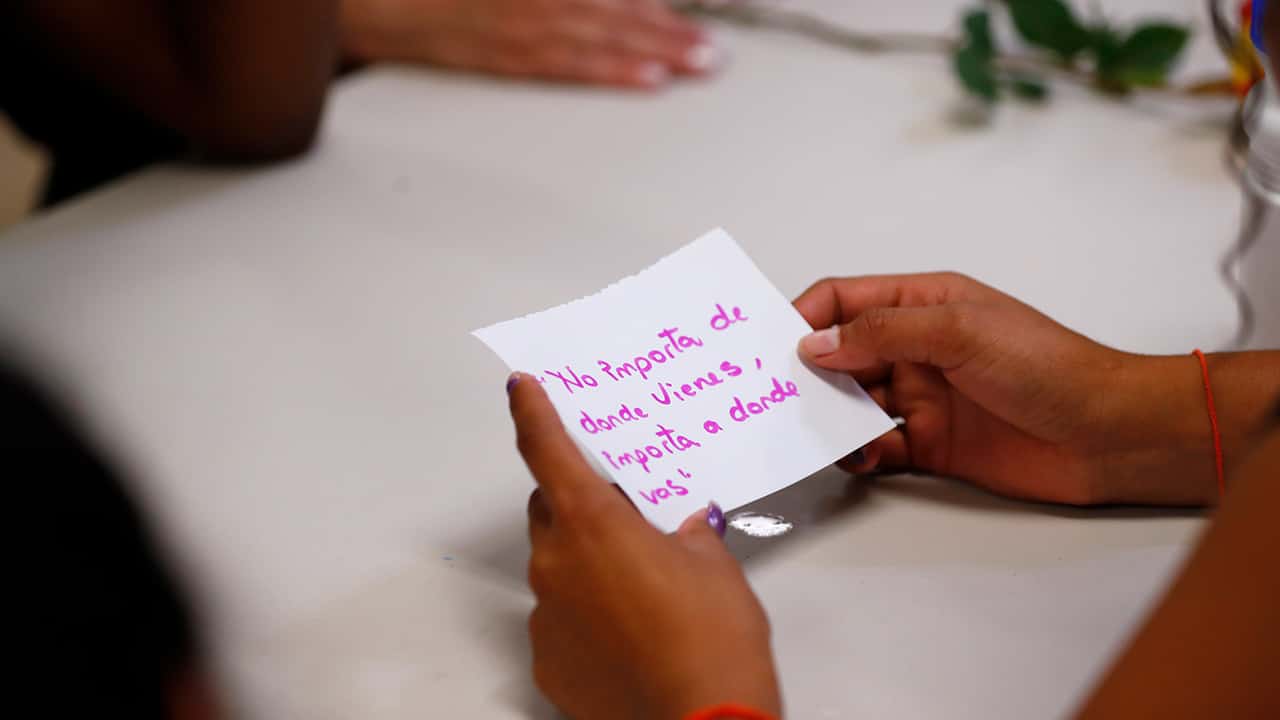 Photo of a migrant girl holding a card