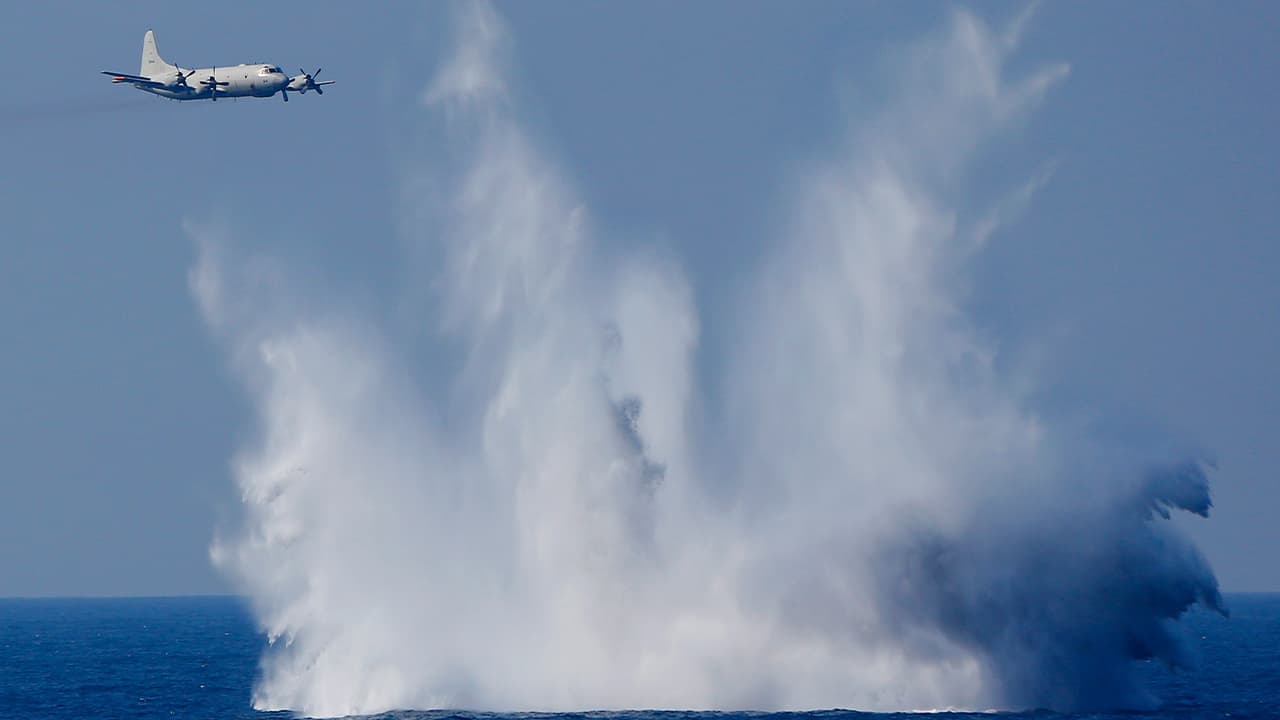 Photo of a P-3C anti-submarine patrol plane of the Japan Maritime Self-Defense Force (JMSDF) flies after dropping anti-submarine bombs during the official triennial JMSDF fleet review in the waters off Sagami Bay, south of Tokyo