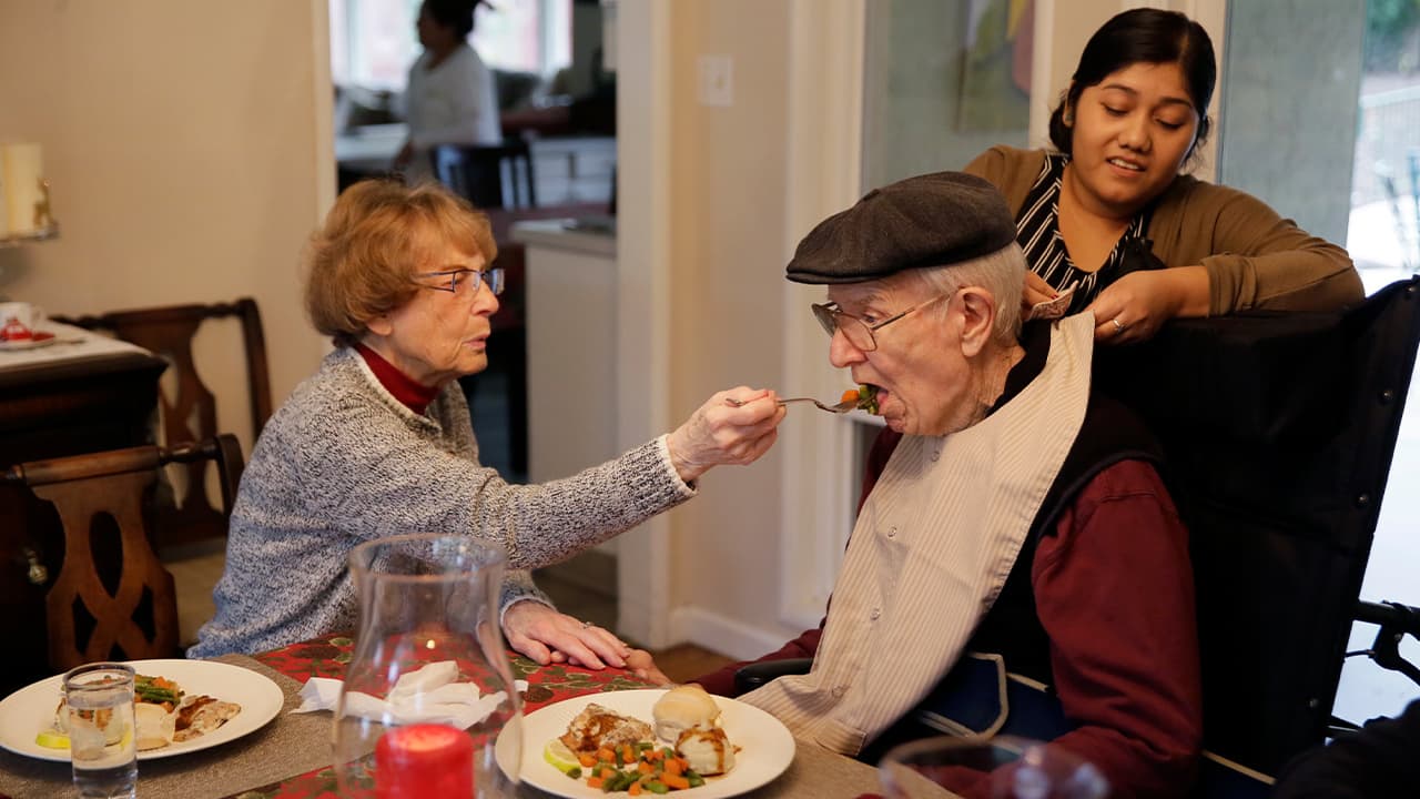Photo of Betty Briggs feeding her husband, Bob