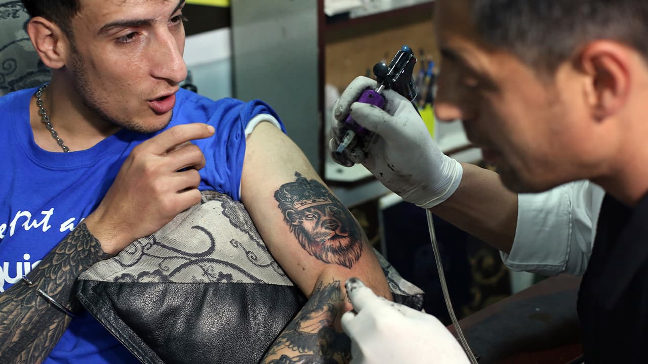 Photo of Omid Noori, 23, getting a lion tattoo in Kabul