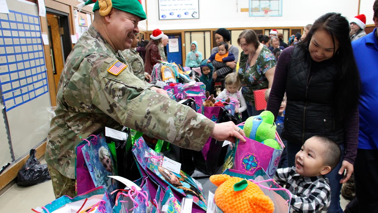 Photo of Alaska National Guard Staff Sgt. Joseph Sallaffie handing a gift bag to Corban Jimmy while Marlene Black looks on