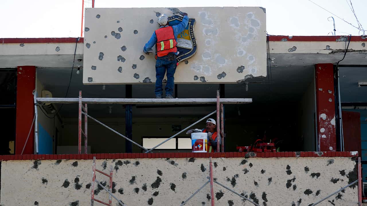 Photo of workers repairing the damage done to the facade of City Hall, Mexico