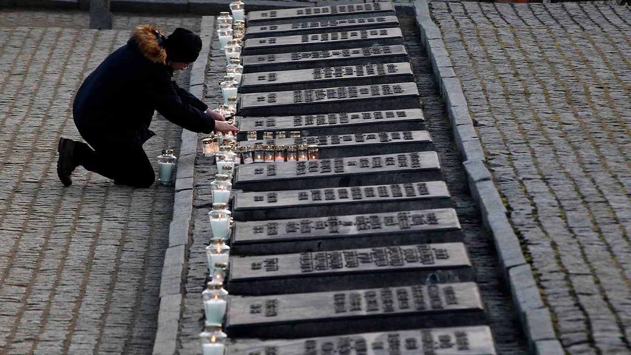 Photo of a person lighting a cancle at the Auschwitz Nazi death camp in Oswiecim, Poland