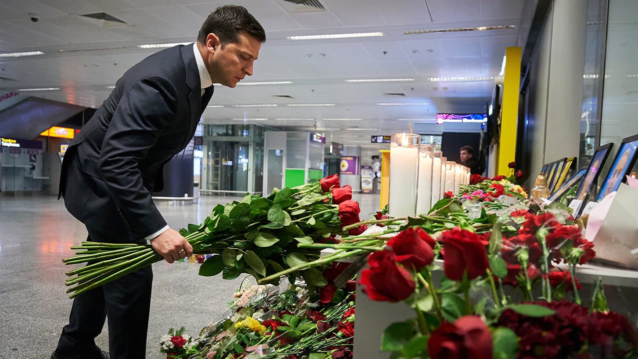 Photo of a man laying flowers at a memorial of the flight crew members of the Ukrainian 737-800 plane that crashed on the outskirts of Tehran