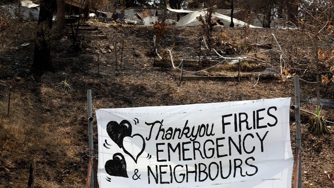 Photo of a sign displayed beside a burned house in Australia