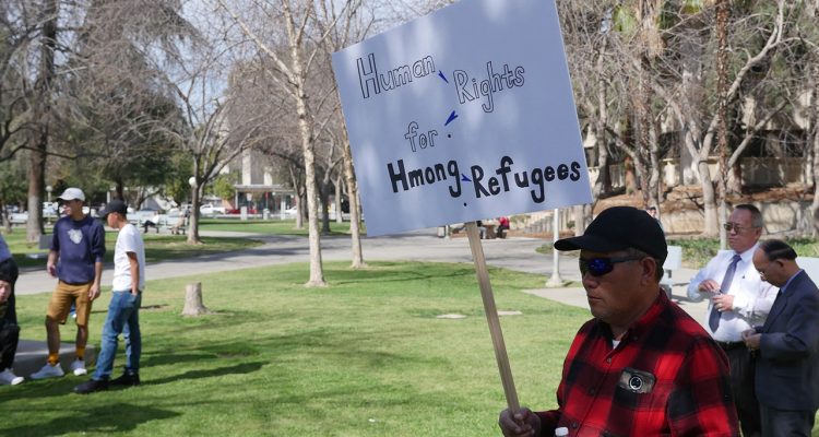 Photo of a man holding a sign at a Hmong rally