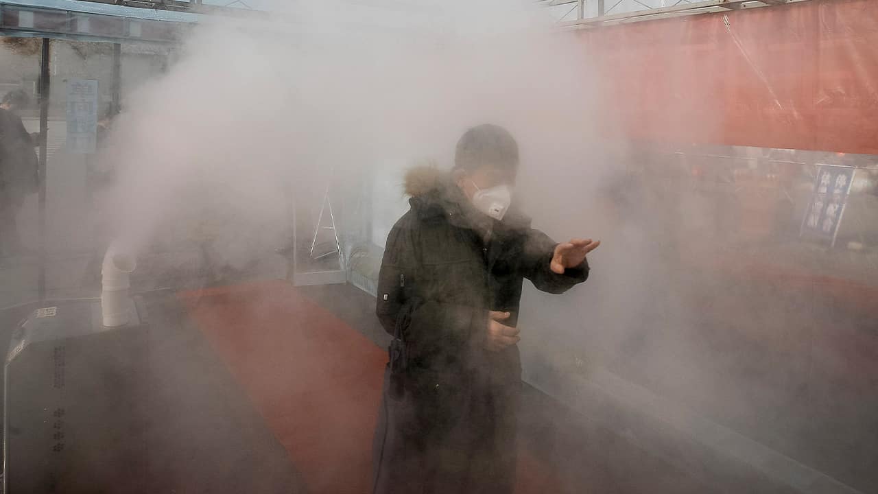 Photo of a man walking through a disinfectant spray in order to return home