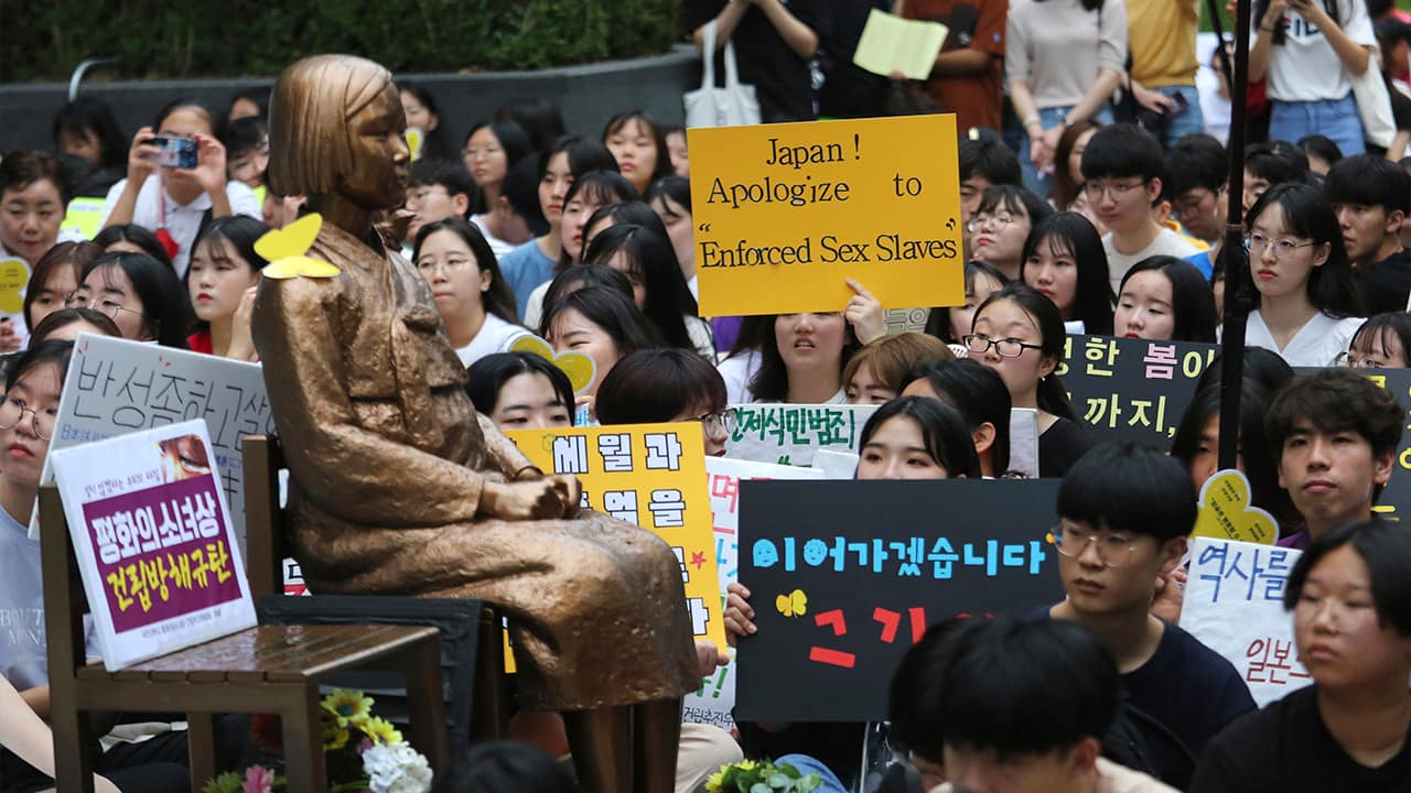 Photo of protesters staging a rally demanding full compensation and an apology for wartime sex slaves from Japanese government near a statue symbolizing sex slaves