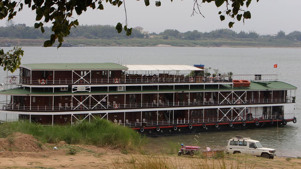 Photo of a cruise boat docked along the Mekong River bank in Kampong Cham, Cambodia