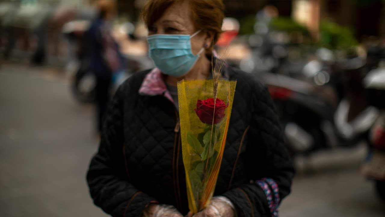 Photo of a woman wearing a face mask and holding a rose in Barcelona