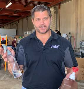 Photo of Dan Riley with bottles of hand sanitizer
