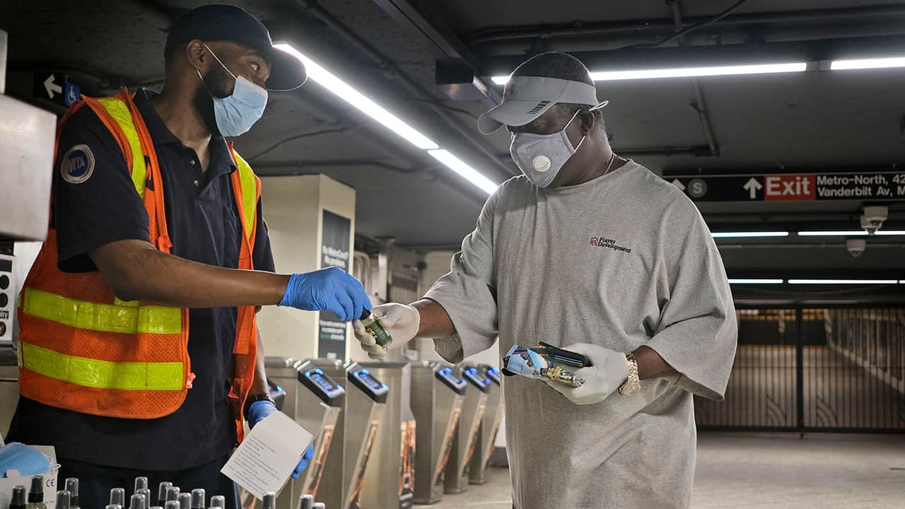 Photo of an MTA employee giving away masks and sanitizer