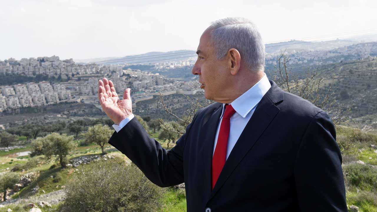 Image of Benjamin Netanyahu on a hill looking down on a West Bank neighborhood