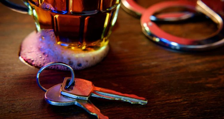 Image of a beer glass, handcuffs and car keys signifying drunken driving arrest